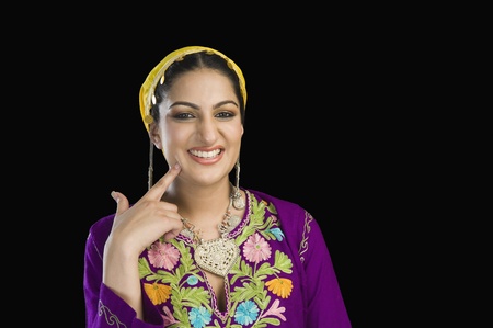 Beautiful woman in Kashmiri dress smiling and touching her cheek