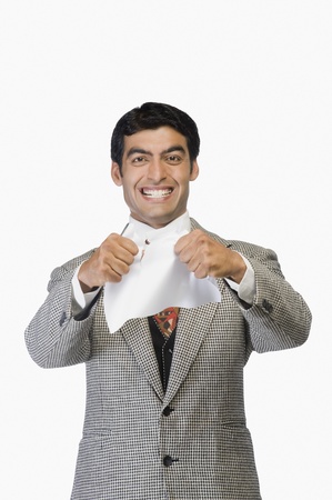 Businessman smiling and tearing a sheet of paperの写真素材