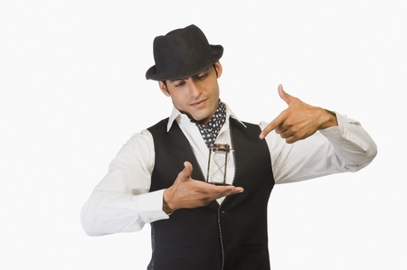 Businessman holding an hourglass and pointing at itの写真素材