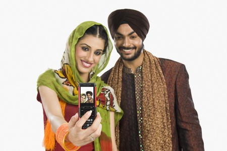 Sikh couple taking a picture of themselves with a mobile phoneの写真素材
