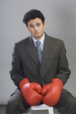 Bruised businessman wearing boxing glovesの写真素材