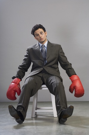 Bruised businessman wearing boxing glovesの写真素材