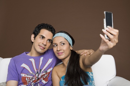 Couple taking a picture of themselves with a mobile phoneの写真素材