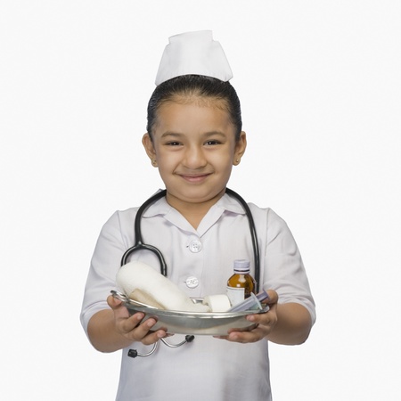 Girl dressed as a nurse and holding a tray of medicines and smilingの写真素材