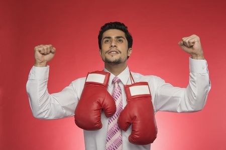 Businessman with boxing gloves clenching his fistsの写真素材