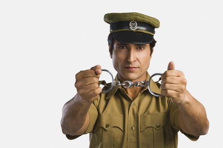 Portrait of a policeman holding a pair of handcuffsの写真素材