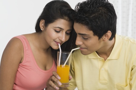 Couple sharing juice from a glassの写真素材