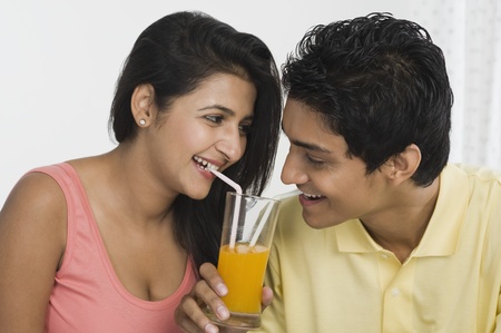 Couple sharing juice from a glassの写真素材