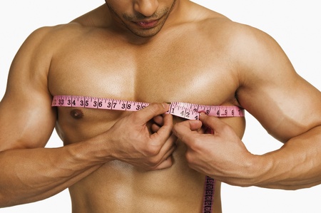 Close-up of a man measuring his chest with a tape measureの写真素材