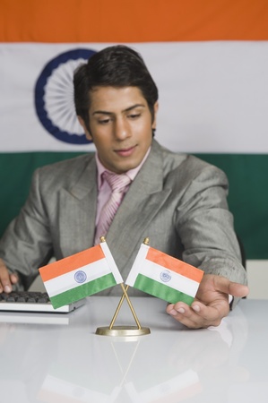 Close-up of a businessman touching Indian flags on the desk in front of himの写真素材