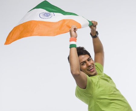 Portrait of a man holding aloft an Indian flagの写真素材