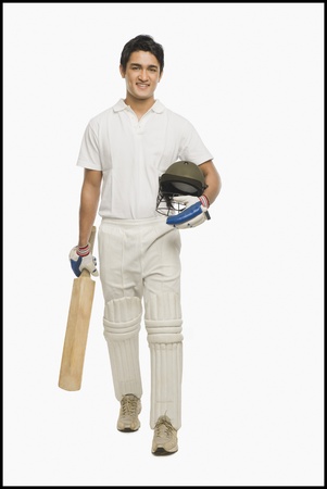 Portrait of a cricket batsman walking with a bat and a helmetの写真素材