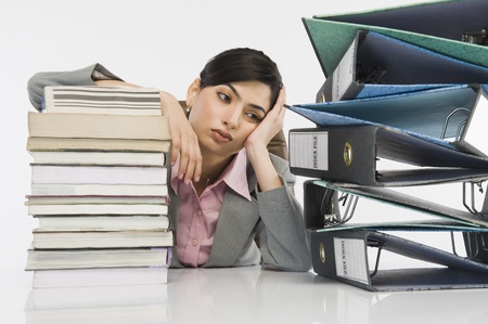 Stack of books in front of a businesswoman at deskの写真素材