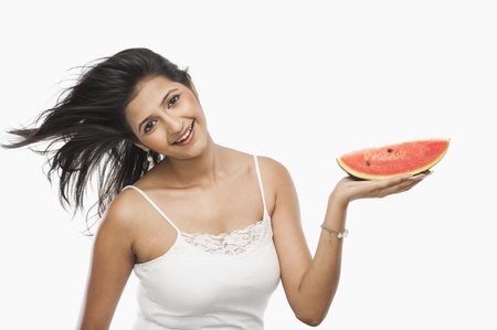 Woman holding slice of watermelon and laughingの写真素材