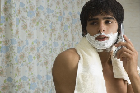 Man talking on a mobile phone in the bathroomの写真素材