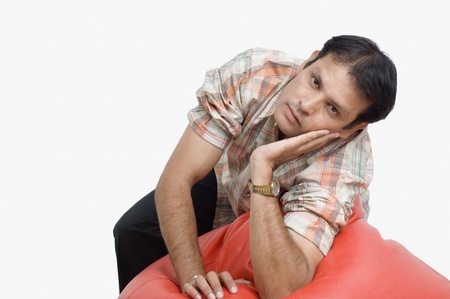 Man leaning on a bean bag and thinkingの写真素材