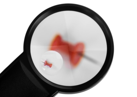 Close-up of a magnifying glass with a thumbtackの写真素材