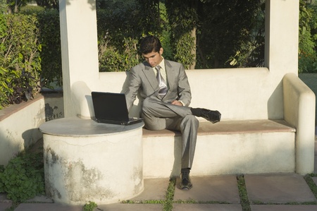 Businessman using a laptop in a parkの写真素材