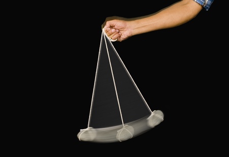 Close-up of a person's hand swinging a stone pendulum