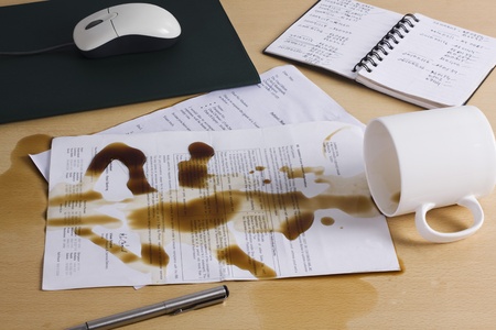 Spilt coffee over documents on a deskの写真素材
