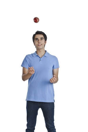 Man tossing a cricket ball and smiling