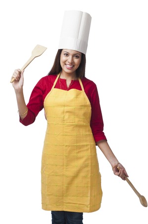 Portrait of a happy woman holding a spatula and ladleの写真素材