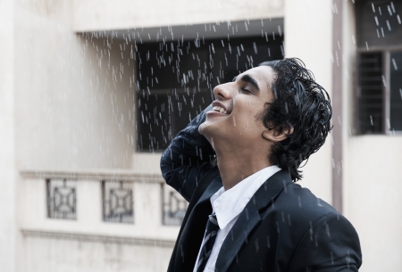 Happy businessman enjoying in the rainの写真素材