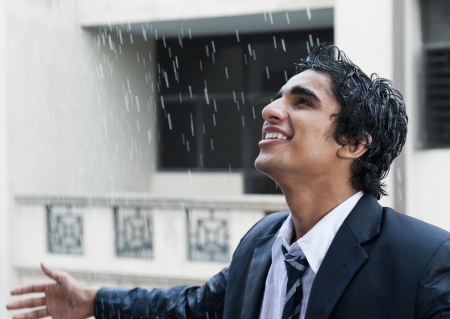 Happy businessman enjoying in the rainの写真素材