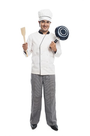 Portrait of a male chef holding a frying pan with spatula and smilingの写真素材