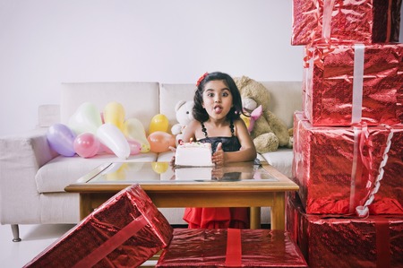 Portrait of a girl standing in front of a cake and sticking her tongue outの写真素材