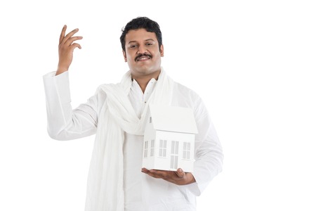 Portrait of a man holding a model home and gesturingの写真素材