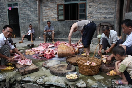 Small group of people cutting raw pork meatのeditorial素材