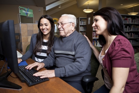 Volunteers teaching a senior how to use a computer の写真素材