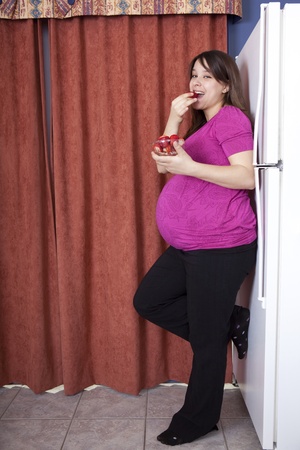 Young pregnant woman eating strawberries の写真素材