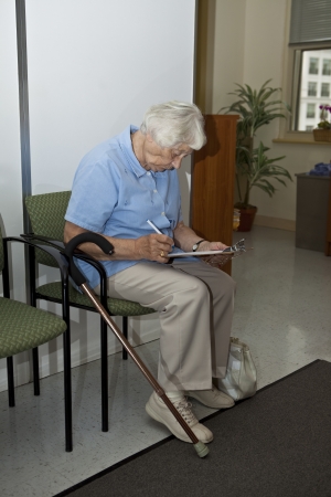 Senior woman filling out forms at the doctor`s office の写真素材