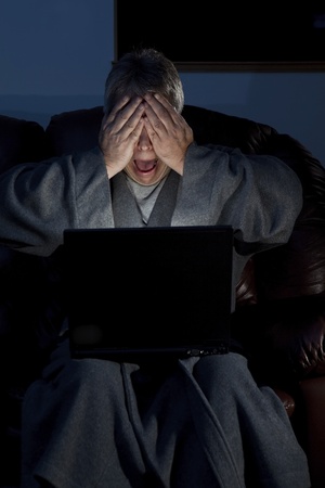 Man in housecoat working late series shocked computer crash の写真素材