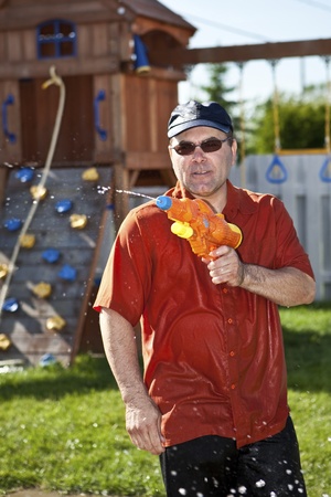 Mature man in a water gun fight の写真素材