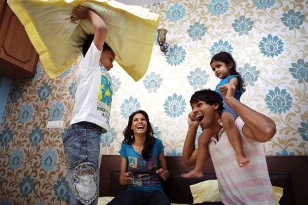 Parents and their kids having pillow fight on bedの写真素材