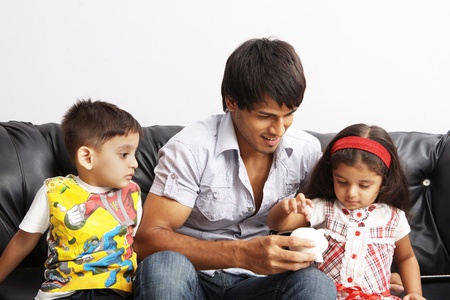 Father and kids putting coins into a piggy bankの写真素材