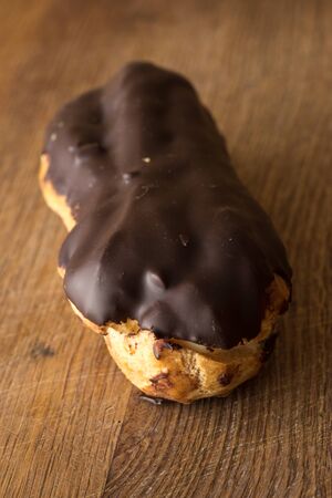 Close up of chocolate eclair on brown wooden board