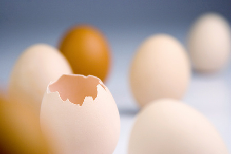 A broken egg standing among other whole eggs