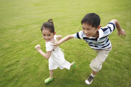 Brother and sister running in the park