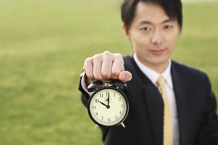 Businessman holding an alarm clock