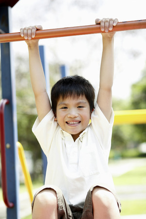 Boy hanging on monkey bars at playground