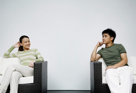Man and woman sitting on couch, looking at each other