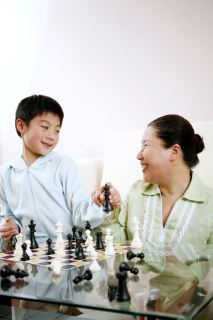 Senior woman and boy playing chess gameの写真素材