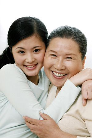 Woman hugging senior woman while smiling at the cameraの写真素材