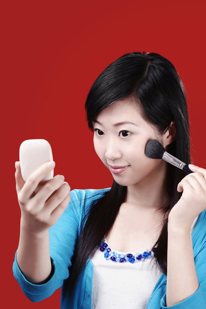Woman applying blusher on her cheekの写真素材