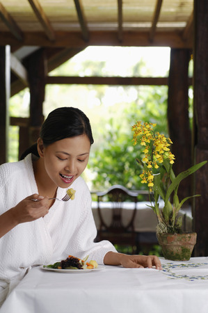Woman in bathrobe eating saladの写真素材