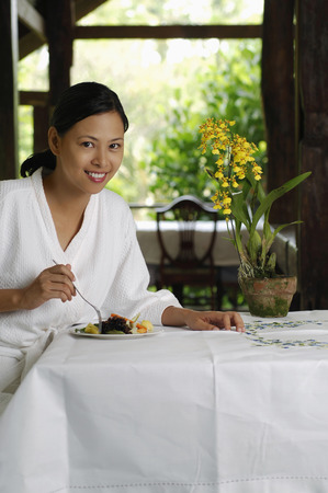 Woman in bathrobe eating saladの写真素材